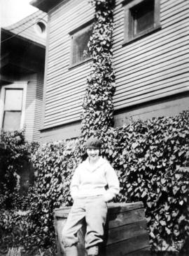 [Woman leaning against wooden crate at side of building at Summit Lake]