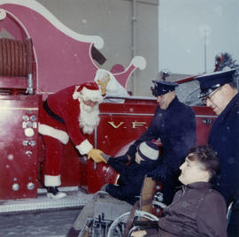 [Firefighter Santa Claus shaking hands with children in wheelchairs]