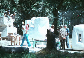Several carvings in process, members of public strolling by