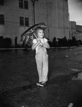 Young girl with umbrella standing by the P.N.E. Forum