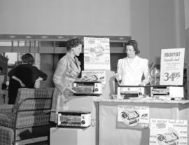 [Woman demonstrating a] Moffat ["Handi-Chef" portable range]