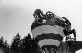 Men performing bike tricks with hot air balloon in background