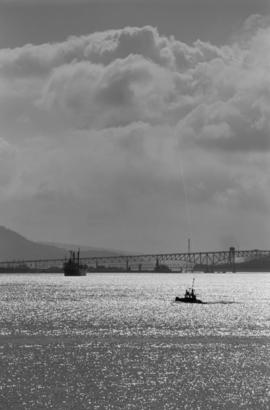 Morning shine [view of Second Narrows Bridge with freighter and small boat in the foreground]