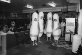 Four people dressed in bowling pin costumes