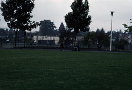 [Two people in wheelchairs on running track]