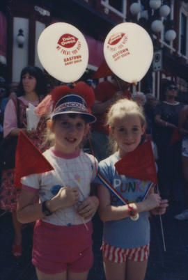 Two girls holding flags and balloons