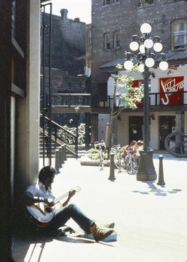 [Man playing guitar in Blood Alley Square]