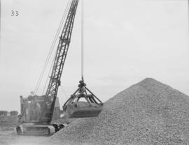 Crawler stockpiling coarse aggregate behind gravel bin