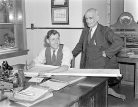 [Two men looking at blueprint drawings in a B.C. Telephone office]