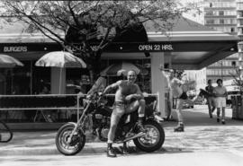 [Man posing with motorcycle outside of] Hamburger Mary's