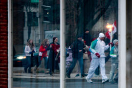 Day 52 Torchbearer and crowd reflection as they pass a window front in Ontario.