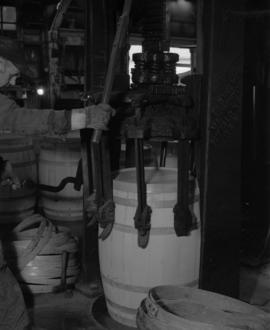 Worker operating machine applying a band to barrel