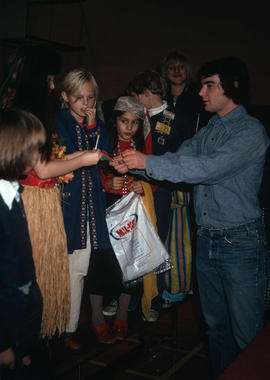 [Man giving darts to children in costumes]