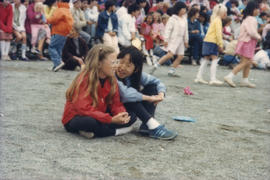 Two girls sitting on gravel and talking