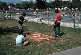 [Boys playing box hockey next to outdoor pool]
