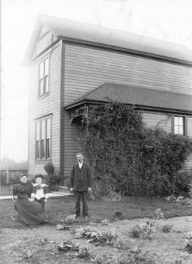 [Mr. and Mrs. Peter McLean and their son Everett beside their house at 453 West 6th Avenue]