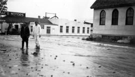 Two men standing in front of Mac's Motors on flooded street