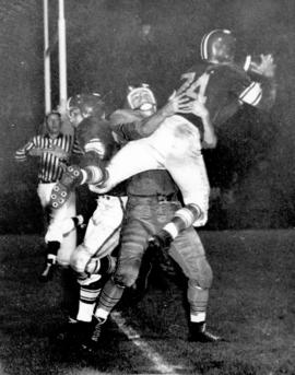 [A player is tackled during the 43rd Grey Cup game at Empire Stadium]
