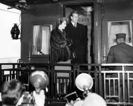 Queen Elizabeth and Prince Philip standing on the back of a railcar