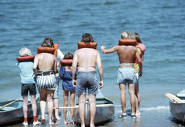 Group with lifejackets and canoes at shore
