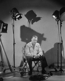Studio shots with lights, enlargers, etc. [Don Coltman seated in studio with lights and camera]