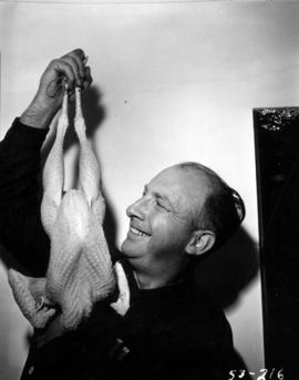 Man holding up a plucked chicken