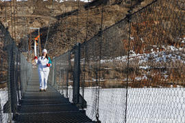 Day 79 Torchbearer 53 Amber Brown carries the flame on the Suspension Bridge in Rosedale, Alberta