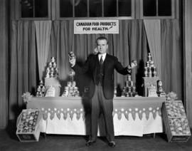 Dr. McCoy at Hotel Vancouver [in front of display of Canadian Food Products for Health]