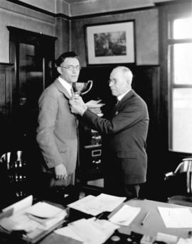 [Mayor L.D. Taylor pinning object to young man's lapel in Mayor's office at old city hall]