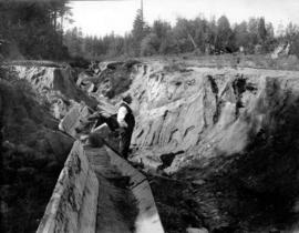 [Man standing in a ditch south of Marine Drive]