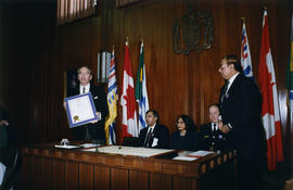 Philip Owen holding up proclamation at International Day to End Racial Discrimination ceremony in...