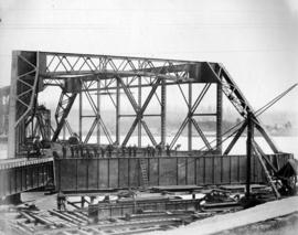[A group of workers pose during the construction of a spread span]