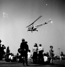 Helicopter hovering over P.N.E. grounds as children watch below