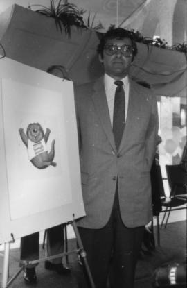 Michael Francis beside a drawing of the official Centennial mascot Tillicum