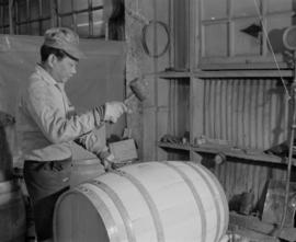 Worker hammering plug into barrel