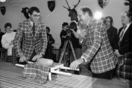 Michael Francis and Mike Harcourt dressed in Centennial tartan placing haggis on table