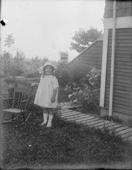 A Salter girl standing beside rocking chair outside