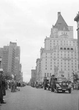 [A parade of military vehicles travelling west along Georgia Street]