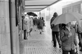 Pedestrians on sidewalk under Birk's Building awning