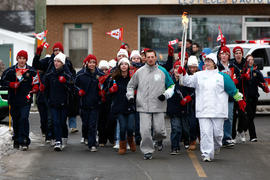 Day 32 Torchbearer 46 Kimberley Sears runs the flame with a crowd in Mont-Joli, Quebec.