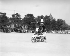 [Four stunt riders on a motorcycle on the Beatty Street drill grounds]