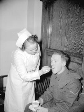 [Nurse taking Cpl. W. F. McClintoch's temperature at a blood donor clinic]