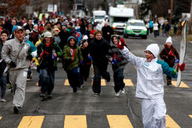 Day 36 Torchbearer 48 Alexandre Breton runs the flame with a crowd in Saint-Romuald, Quebec.
