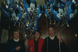 Three people holding Mickey Mouse balloons at City Hall