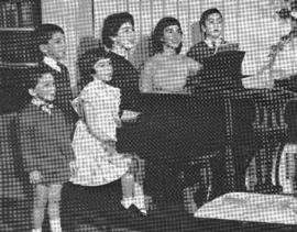 Group of children surrounding a piano