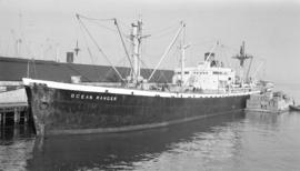 S.S. Ocean Ranger [at dock, with lumber-filled barges alongside]