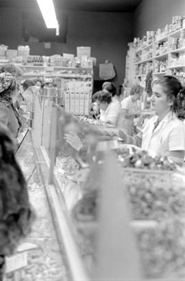 Interior of unidentified grocery store with shoppers, clerks, and stock