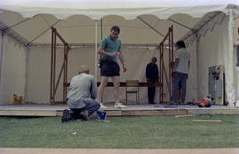 Group setting up white event tent