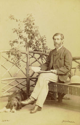 [Studio portrait of man with dog at his feet and maple branch in the background]