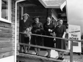 Four ladies on steps of P.N.E. program prize home